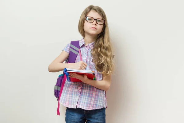 Mladá školačka v brýlích a s batohem píše do školy notebook. — Stock fotografie