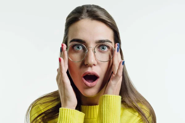 Surprised young woman in yellow sweater with glasses over white background — Stock Photo, Image