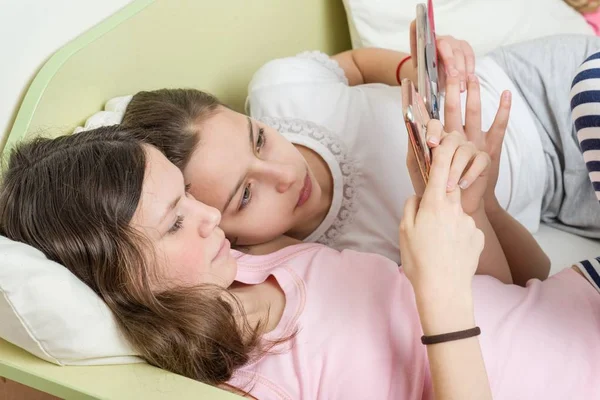 Meisjes tieners met belangstelling kijken naar hun favoriete tiener Tv-serie op hun smartphone. Liggen in bed thuis in zijn kamer — Stockfoto