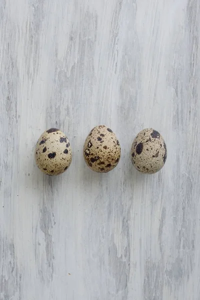 Три перепелиных яйца на белом винтажном фоне — стоковое фото