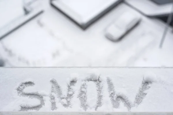 Nevadas en la ciudad, vista desde la ventana de un edificio de varios pisos. La palabra SNOW en el alféizar cubierto de nieve , —  Fotos de Stock