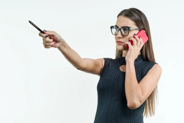 Donna d'affari in occhiali vestito nero con punti telefonici con una penna su spazio copia. Bianco sfondo Studio . — Foto Stock