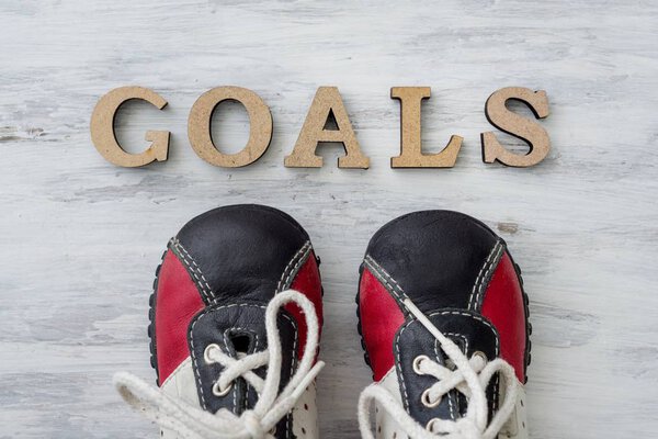 Sneakers on light surface in front of the word goals