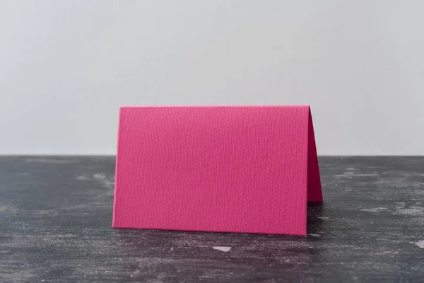 Tarjeta rosa en blanco sobre mesa oscura. Fondo claro — Foto de Stock