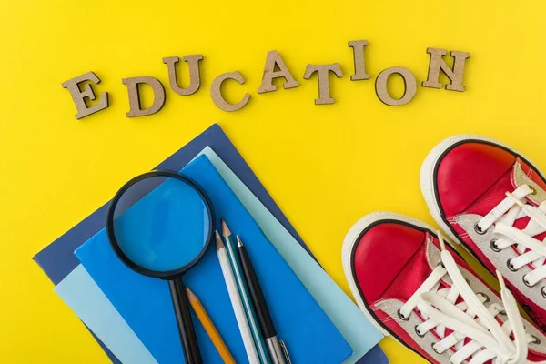 O conceito de educação. Tênis vermelhos, material escolar, livros, cadernos com fundo amarelo . — Fotografia de Stock