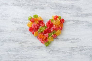 Beyaz ahşap antika arka plan ile kalp şeklinde çok renkli meyve şekerlenmiş