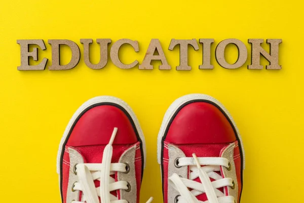 Концепція освіти. Слово виховання червоні дитячі кросівки з жовтим тлом . — стокове фото