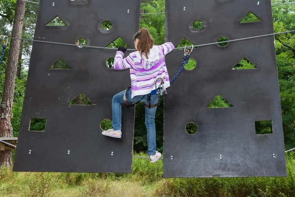 A menina tem 10 anos de idade em aventura escalando o parque de arame alto, visão traseira, estilo de vida ativo de crianças — Fotografia de Stock