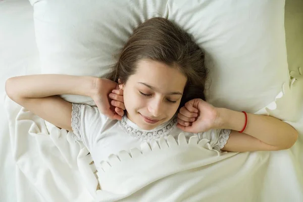 Goedemorgen, tienermeisje wakker en glimlacht liggend op een kussen in haar bed, bovenaanzicht — Stockfoto