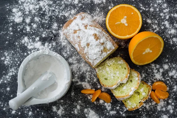 Minzkuchen mit Puderzucker bestreut auf dunkler Oberfläche mit frischen Orangen-Mandarinen. — Stockfoto