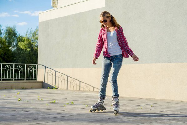 Active sportsl teen gir in roller skates, urban background.