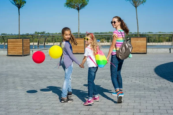 Arkadan görünüşü çocuk kız öğrenciler tutan eller birlikte açık havada kentsel yolda arka plan yürümek. — Stok fotoğraf