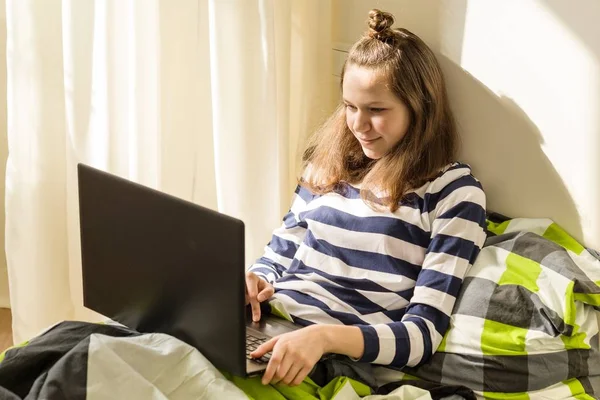 Adolescente ragazza utilizza il computer portatile a letto a casa — Foto Stock