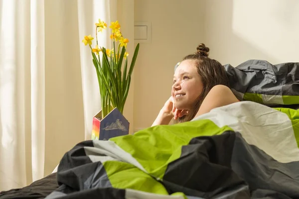Menina adolescente e buquê de flores amarelas da primavera. Cama de fundo no quarto — Fotografia de Stock