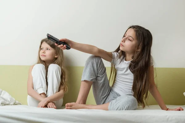 Meisjes childs zitten thuis in bed en Tv kijken. In de handen met tv remote — Stockfoto