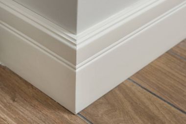 Molding in the interior, baseboard corner. Light matte wall with tiles immitating hardwood flooring clipart