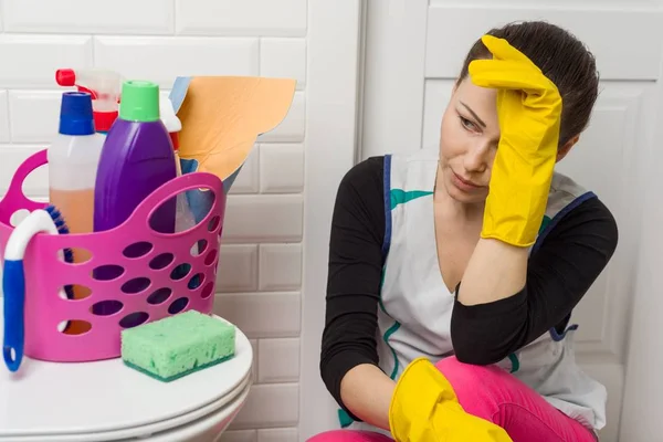 Temizlik malzemeleri ve ekipmanları ile banyo katta oturan yorgun kadın — Stok fotoğraf