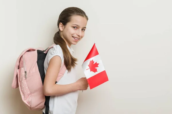 Studentessa 10 anni in T-shirt bianca con uno zaino che tiene la bandiera del Canada — Foto Stock