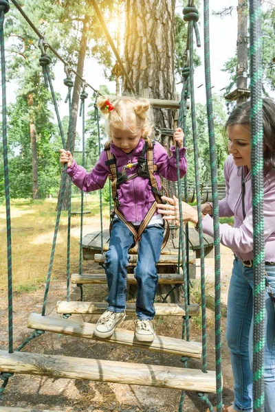 Moeder helpt zijn dochtertje geschiedde obstakels in adventure klimmen high wire park, actieve levensstijl van kinderen — Stockfoto