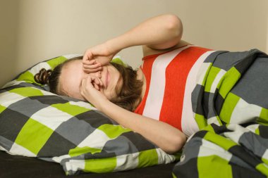 Genç kız uyandığında, gözlerini ovuyor. Yatakta, üstten görünüm bir yastık üzerinde yalan