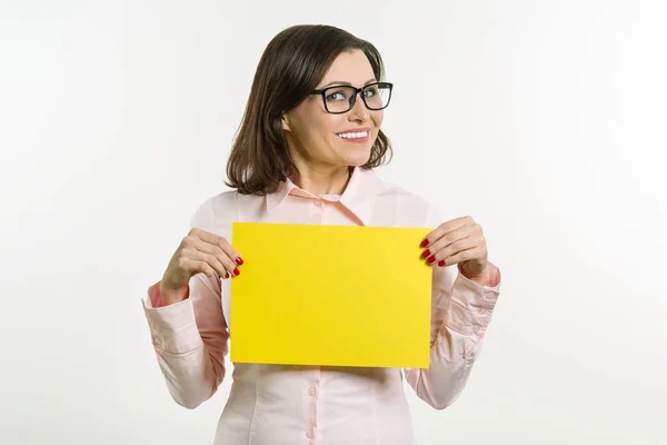 Lächelnde Frau mittleren Alters mit gelbem Blatt Papier auf weißem Hintergrund — Stockfoto