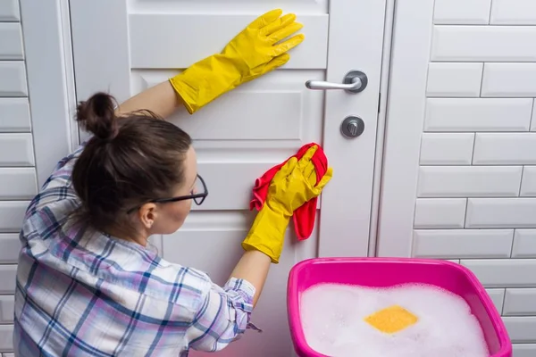 Professional cleaning service. Woman housekeeper wipes the door with rag. — Stock Photo, Image