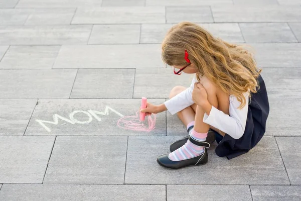 С Днем Матери. Маленькая девочка рисует для своей матери картинку-сюрприз из карандашей на асфальте. LOVE MOM . — стоковое фото