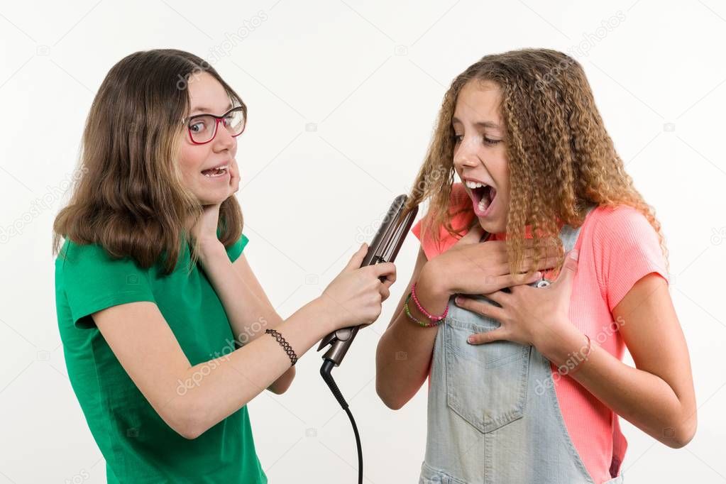 Portrait of two teenage girlfriends doing hairstyle at home. White background