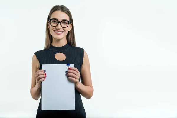 Positiv leende affärskvinna i glasögon svart klänning visar en ren vit dokument med kopia utrymme. Vit bakgrund. — Stockfoto