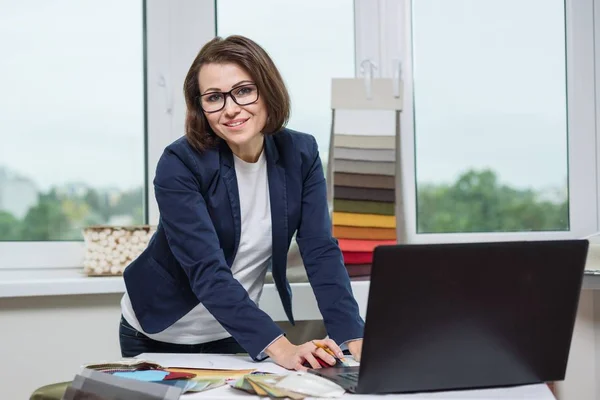 Designer eller arkitekt poserar och tittar på dig fungerar med prover av tyger för gardiner och persienner, bakgrunden office fönster. — Stockfoto