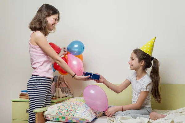 Mañana de cumpleaños. Hermana mayor dando regalo sorpresa a su linda hermanita. Niños en casa en la cama —  Fotos de Stock