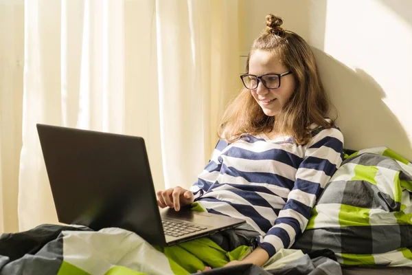 Ragazza adolescente sta studiando a casa, utilizza il computer portatile a letto — Foto Stock
