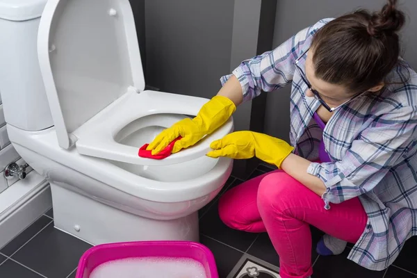 La donna sta pulendo in bagno. Lavare la toilette — Foto Stock