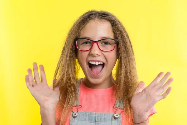 Ευτυχισμένος έφηβη κοπέλα ξανθιά με σγουρά μαλλιά gesticulating, φωτεινό φόντο κίτρινο στούντιο. — Φωτογραφία Αρχείου