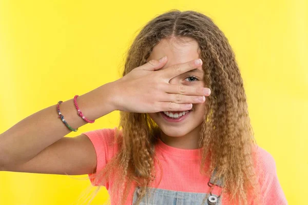 Retrato de menina adolescente espreita através dos dedos. Amarelo estúdio fundo — Fotografia de Stock