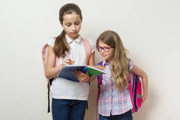 Τα παιδιά το σχολείο τις φίλες. Το μεγαλύτερο κορίτσι δείχνει νεότερος σημειωματάριο. — Φωτογραφία Αρχείου