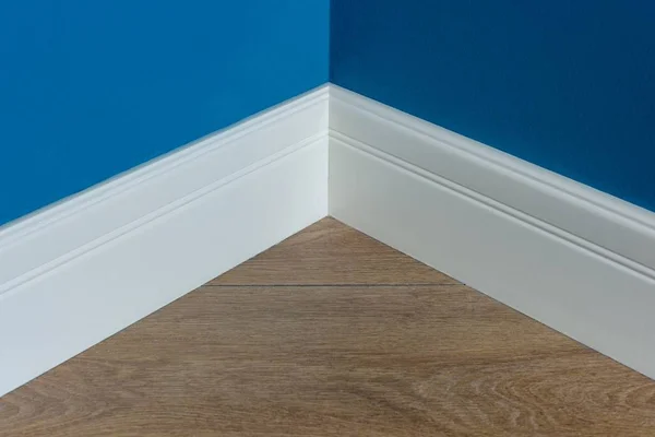 Moulding in the corner. Blue Matte Wall with laminate immitating oak texture — Stock Photo, Image