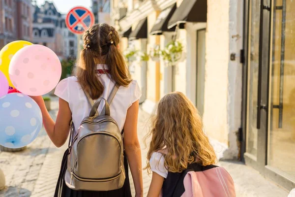 Duas meninas andando ao longo da rua com balões . — Fotografia de Stock