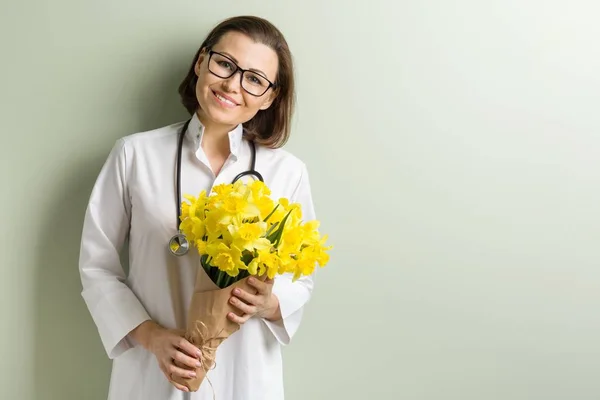 Glimlachende vrouw arts met boeket bloemen. — Stockfoto