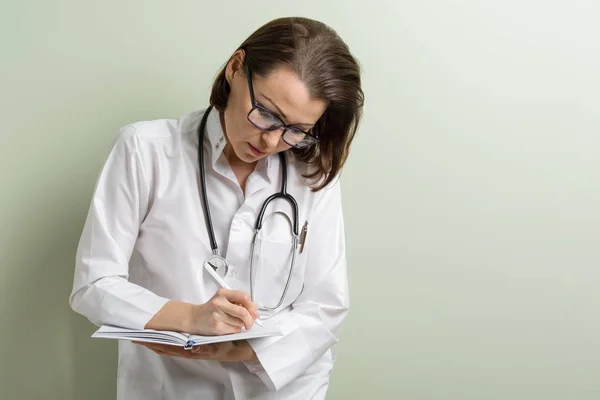 Mulher médica tomando notas em seu bloco de notas — Fotografia de Stock