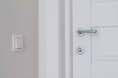 Beyaz iç kapı. Işık duvardaki bej düğmeye