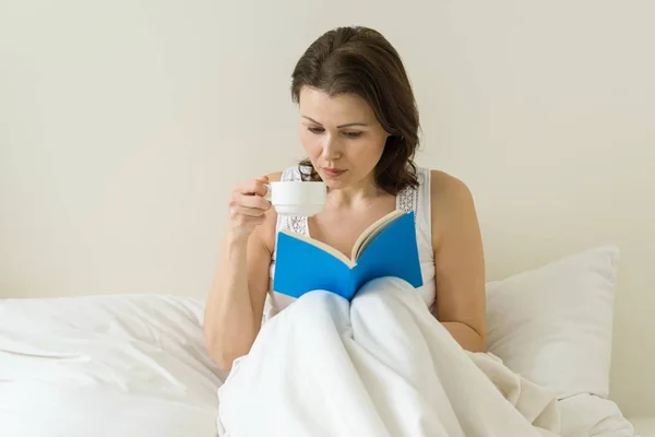 Mulher madura na cama livro de leitura — Fotografia de Stock