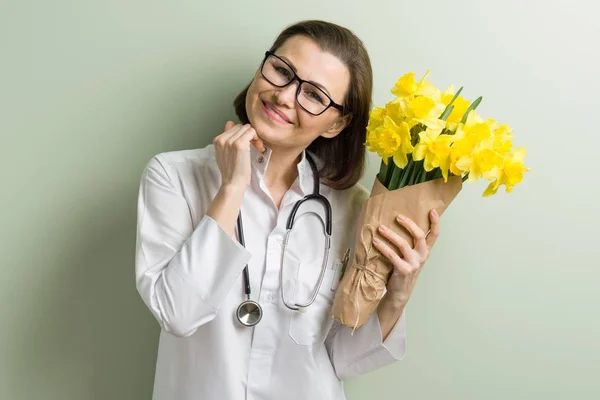 Smiling woman doctor with bouquet of flowers — Stock Photo, Image