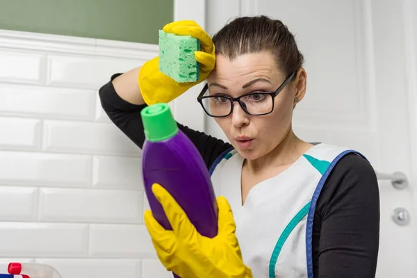 Casalinga donna fa la pulizia con interesse leggendo le istruzioni sul detergente — Foto Stock