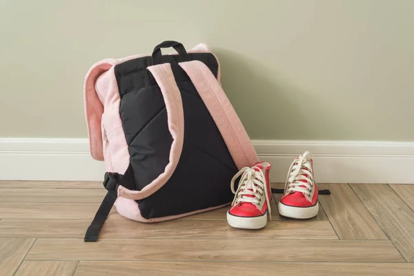 Mochila escolar y zapatillas de deporte en el suelo en el interior del hogar — Foto de Stock
