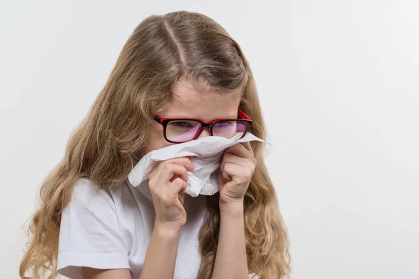 La niña estornuda con el pañuelo. Temporada de gripe, fondo blanco, espacio para copiar . — Foto de Stock