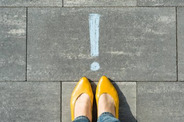 Ünlem işareti simgesi asfalt üzerine çizilmiş dikkat kadın ayakları.