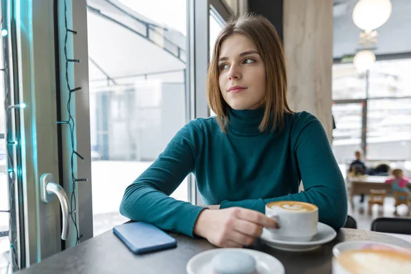 Young woman resting at break in cafe with cup of hot drink — Stock Photo, Image