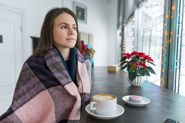 Молода жінка в кафе з чашкою гарячого напою з теплим ковдрою — стокове фото