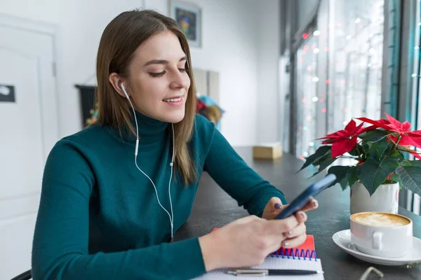 Young woman in headphones using smartphone for work and study